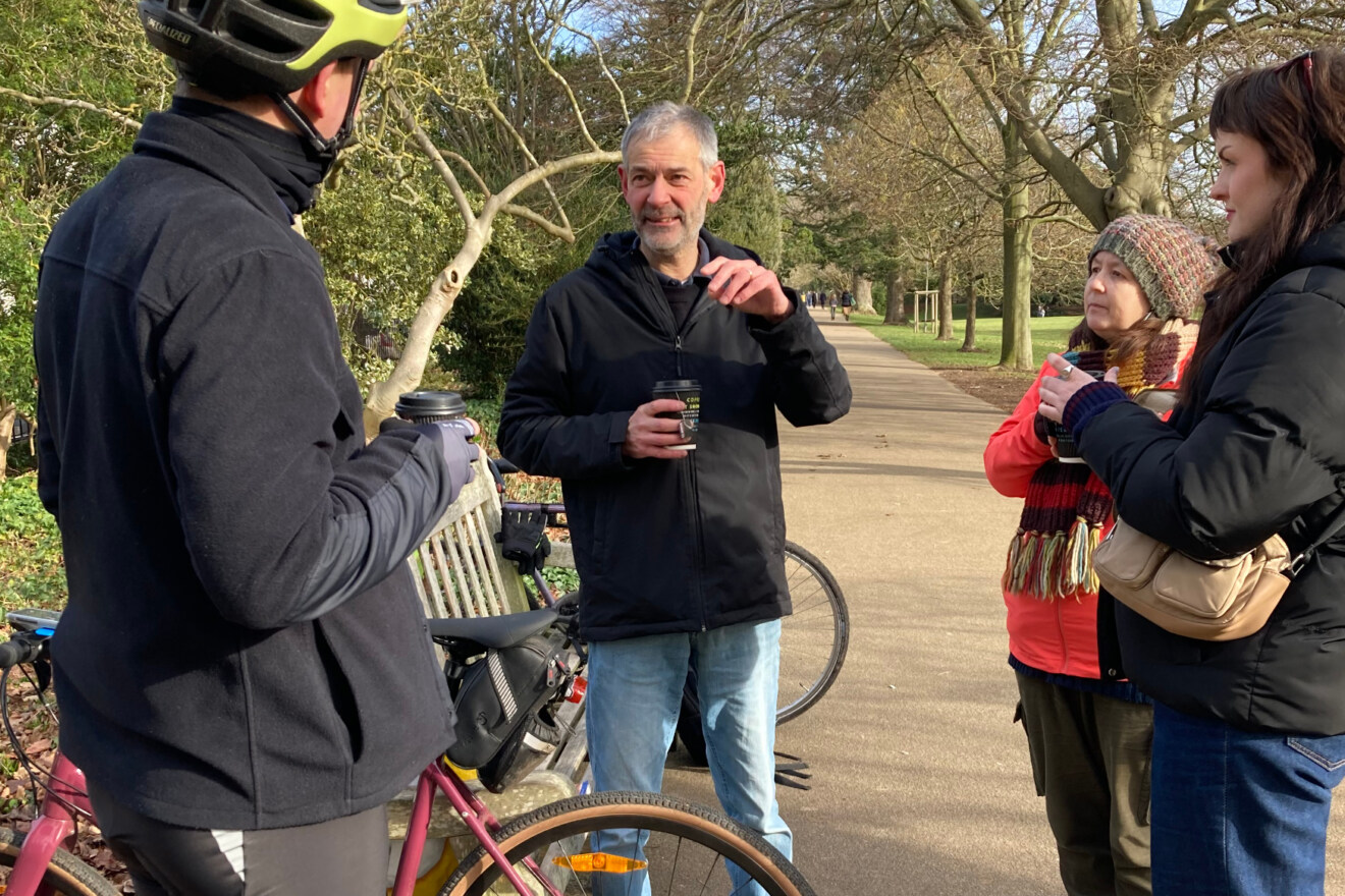 A group of people chat in a park after a bike ride