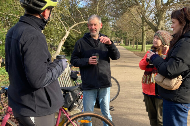 A group of people chat in a park after a bike ride